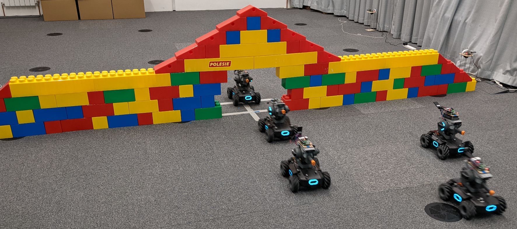 Five DJI RoboMaster robots coordinating through a narrow passage using decentralized GNN policies.